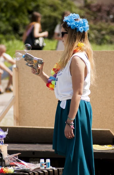 Attractive college girl shooting soap bubbles from toy gun — Stock Photo, Image