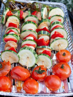 Sebzeli ızgara şişler, tavuk eti ve alüminyum tepsiye konmuş domatesler..