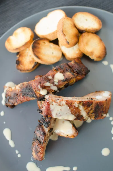 Costeletas na grelha com molho e baguete torrada — Fotografia de Stock