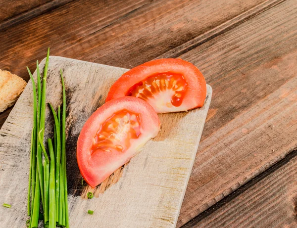 Bieslook met tomaten op houten plaat — Stockfoto