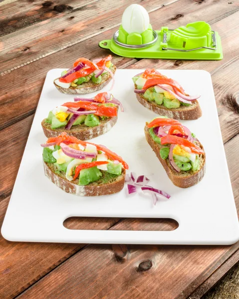 Braunes Brot mit Avocado, Räucherlachs, gekochtem Ei — Stockfoto