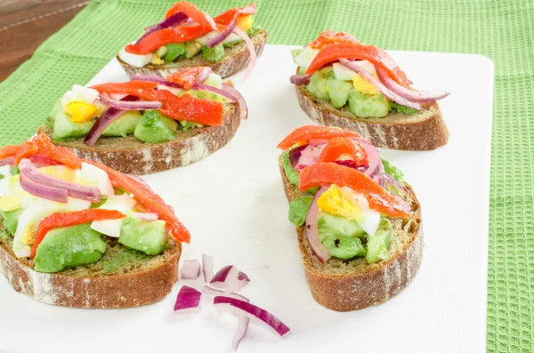 Braunes Brot mit Avocado, Räucherlachs, gekochtem Ei — Stockfoto