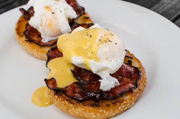 Benedict eggs with crispy bacon and hollandaise sauce on toasted Maffin
