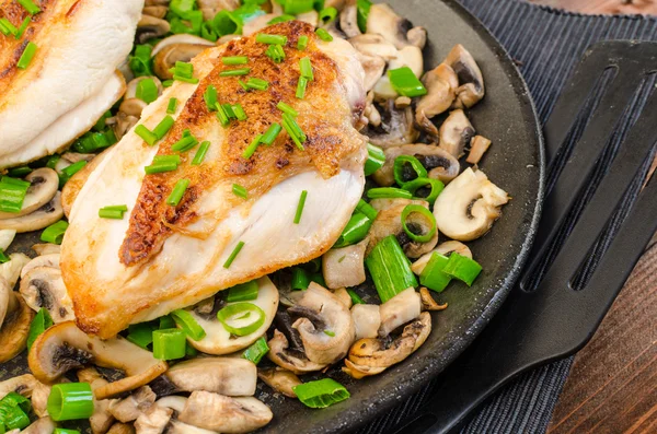 Chicken breast with mushrooms and spring onions on pan