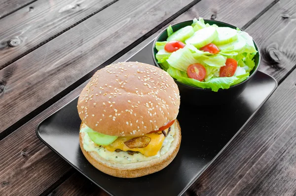 Cheeseburger with bacon and tartar sauce and garden salad — Stock Photo, Image