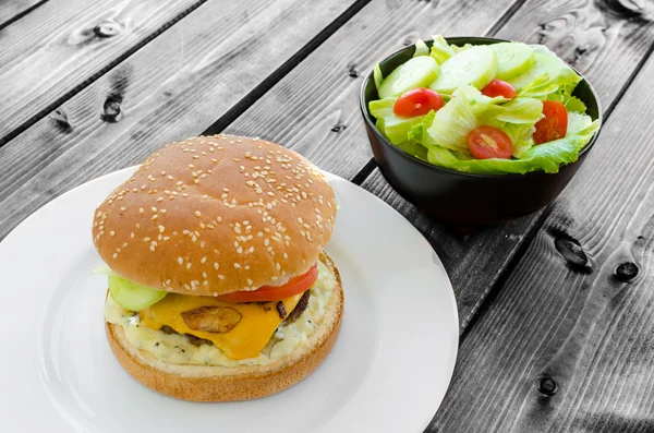 Cheeseburger with bacon and tartar sauce and garden salad — Stock Photo, Image