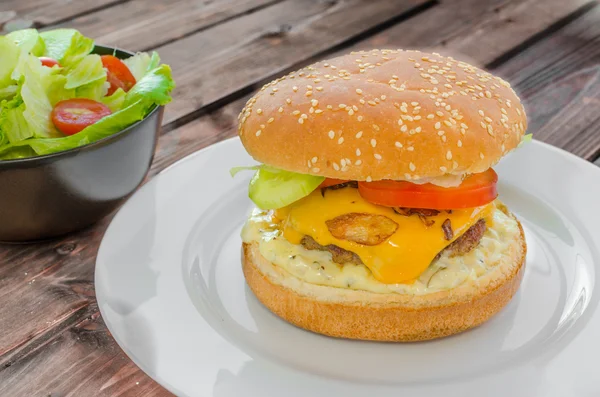 Cheeseburger with bacon and tartar sauce and garden salad — Stock Photo, Image