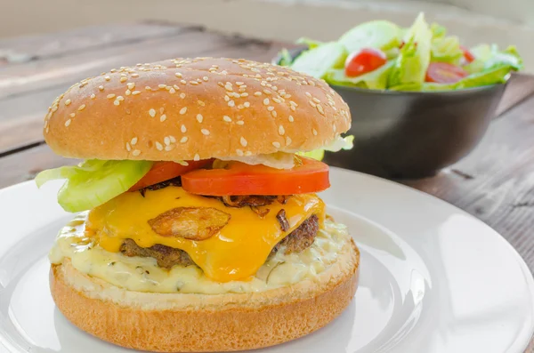 Cheeseburger with bacon and tartar sauce and garden salad — Stock Photo, Image