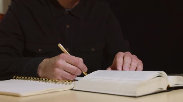 Unbekannter sitzt am Tisch und schreibt etwas in Notizbuch — Stockvideo