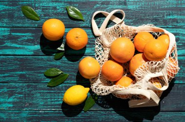 Mavi ahşap arka planda turunçgil meyveli ekolojik ağ torbası..