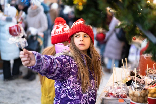 겨울 옷을 입은 두 아이가 크리스마스 마켓에서 사탕을 고르는 모습. — 스톡 사진