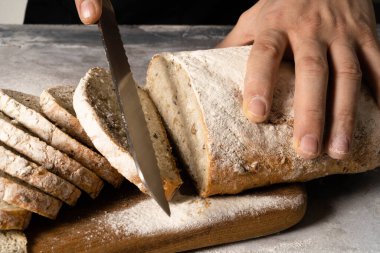 Erkek elleri bir dilim ekmeğe tereyağı sürer..