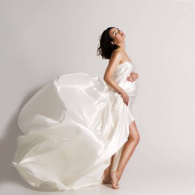 Beyaz ipeğe sarılı hamile kadın..