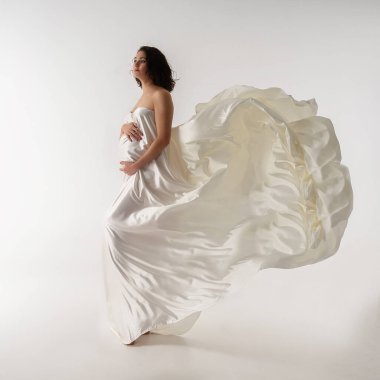 Beyaz ipeğe sarılı hamile kadın..