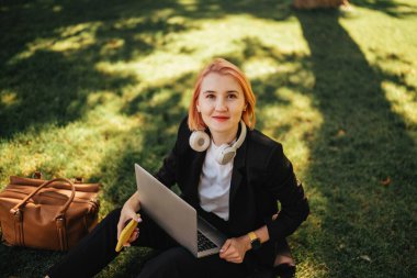 Kafkasyalı güzel bir kadın kahve ve dizüstü bilgisayarla parkta yürüyüşe çıkıyor. Açık havada çalışmak