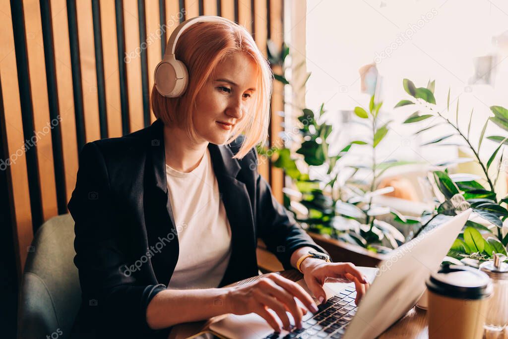Lady freelancer wearing headset, communicating with client via video computer call. Millennial professional female