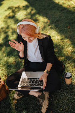 Kafkasyalı güzel bir kadın kahve ve dizüstü bilgisayarla parkta yürüyüşe çıkıyor. Açık havada çalışmak