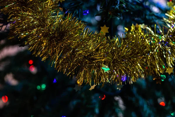 Horizontales Foto einer goldenen Girlandenschleife, um den Weihnachtsbaum mit farbigen Lichtern zu schmücken — Stockfoto