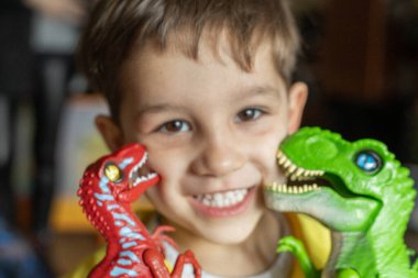 Seçici odaklı iki dinozor tarafından öpülürken gülümseyen bir çocuğun portresi