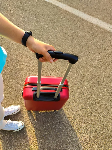 道路の真ん中に赤いスーツケースを着た若い女性が — ストック写真