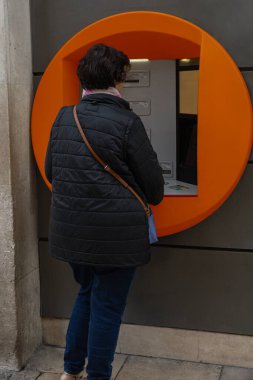 Kadın otomatik veznedar ekonomi konseptinden para çekiyor.