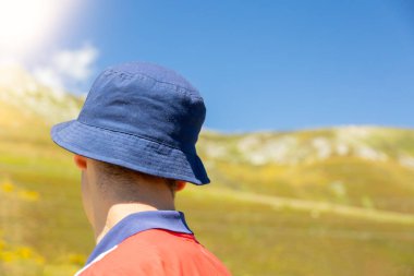 detail of a boy on his back with blue cap in the bush to protect himself from the sun with copy space concept of solitude and future