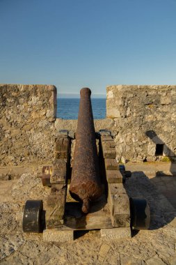 rusty old cannon on the city wall to protect the city in the battle against the ships with selective focus.