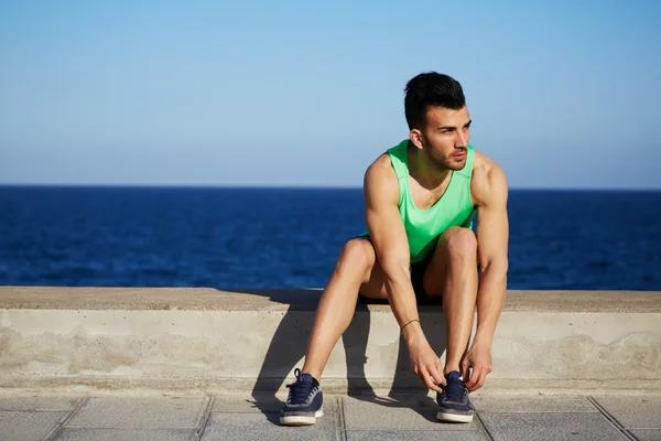 Sedící běžec odpočívá po běhání a vázání tkaničky — Stock fotografie