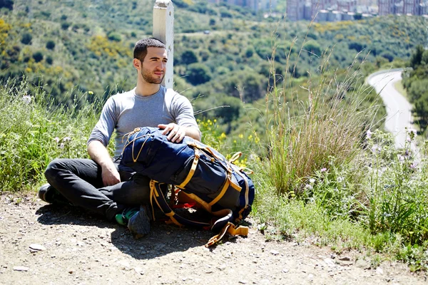 Young traveler resting seated on the hill — Stock Photo, Image
