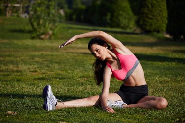 atletik kız güzel park çimenlere oturmuş germe egzersiz yaparak