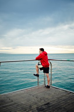 Deniz iskelede duran ve uzağa bakarak adam