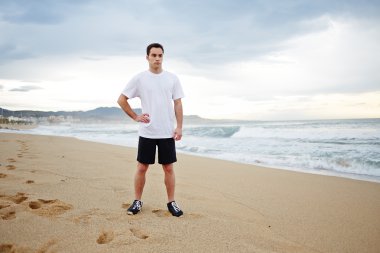 plaj kum üzerinde duran ve uzağa arıyorum genç sporcu adam