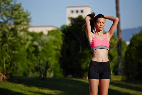 Krásná sportovní dívka stojící v zeleném parku po běhání — Stock fotografie