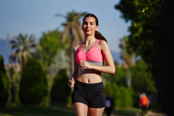 Beautiful athletic girl running in the green park — Stock Photo, Image