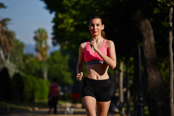 Vakker, atletisk jente som løper i den grønne parken – stockfoto