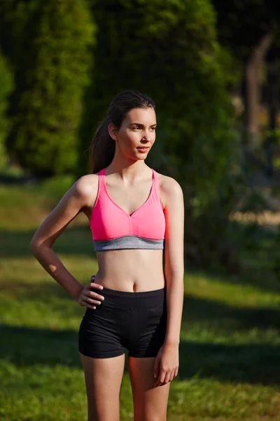 Hermosa chica atlética de pie en el parque verde después de correr —  Fotos de Stock