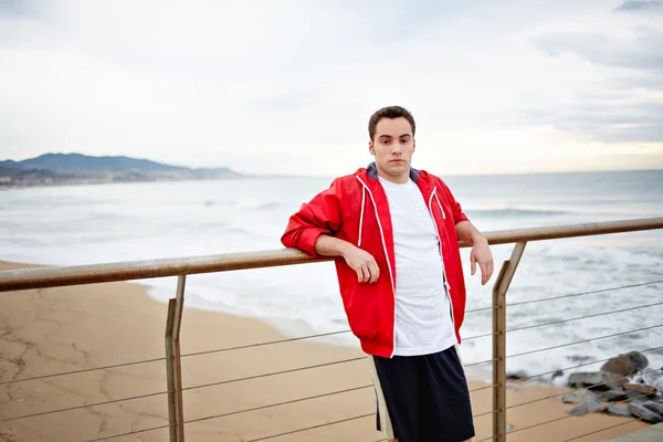 Young athlete man standing on the beach and resting after the morning jogging — Stock Photo, Image