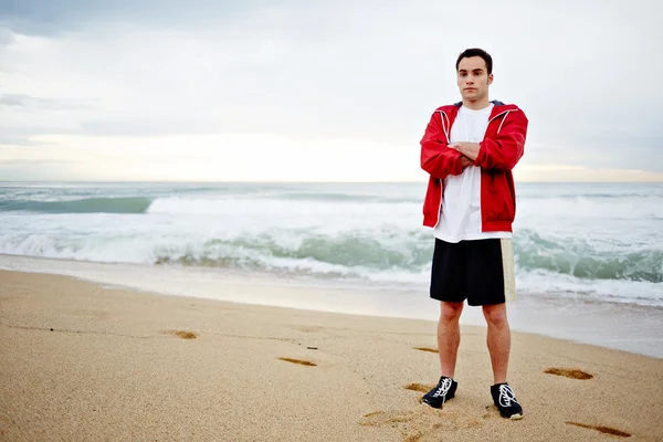 Jonge atleet man rust na de ochtend joggen op het strand — Stockfoto