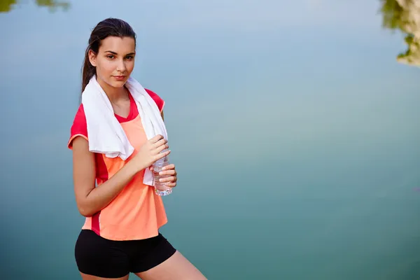 Vrouwelijke atleet na het joggen staat met water in de handen — Stockfoto