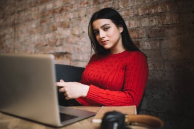 Kafede, duvarın karşısında, netbook ve kulaklıklarla oturmuş, cep telefonlarını karıştıran sakin bir genç bayan.