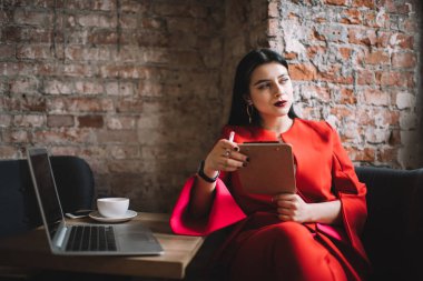Saçı siyah saçlı, rahat kafeteryada dizüstü bilgisayarı açık oturan ve uzaktan çalışırken not alan mutlu bayan.