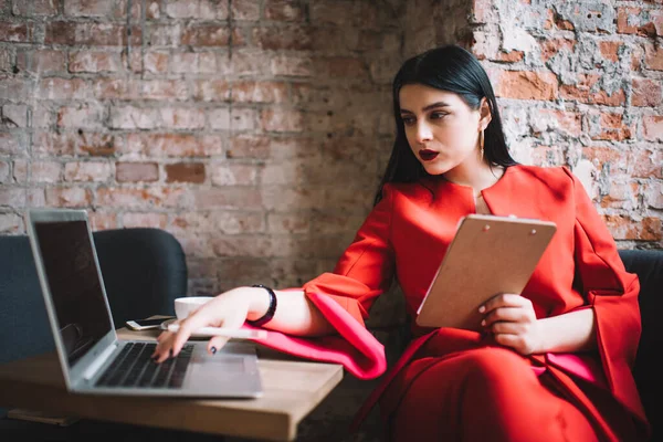 Laptop 'a bilgi yazan ve bir fincan kahveyle çağdaş iş yerinde vakit geçirirken yeni bir ödev üzerinde çalışan odaklanmış bir kadın.