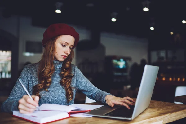 Joven Freelancer Femenina Concentrada Sentada Mesa Escribiendo Notas Encontrando Información —  Fotos de Stock