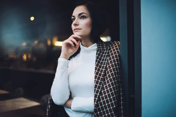 シリアスな若い女性を着てカジュアルな服と現代的なカフェに立ってコートをプレイし 離れて見ている間に壁にもたれて — ストック写真