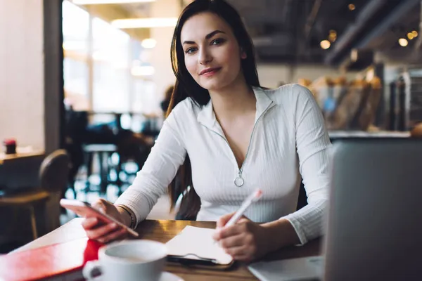 Koncentrerad Kvinnlig Frilansare Tittar Kameran Sitter Vid Bordet Surfa Mobiltelefon — Stockfoto