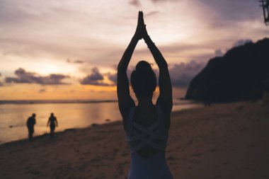 Genç Yogi 'nin namaste' de meditasyon yaparken sırt silueti görüntüsü akşam vakti deniz kenarında asanas pozu, sağlıklı yaşam tarzı mükemmel vücut şekli ve ruhun ahengi.