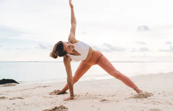 在巴厘岛平静的海滨练习瑜伽时 身材苗条 头戴发髻 腿穿三角裤的柔韧女性 — 图库照片