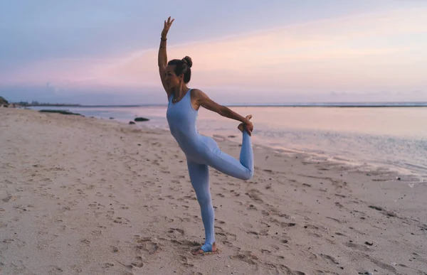 夏至时赤脚女穿着活动服装在海边沙滩上做瑜伽的侧视图 — 图库照片