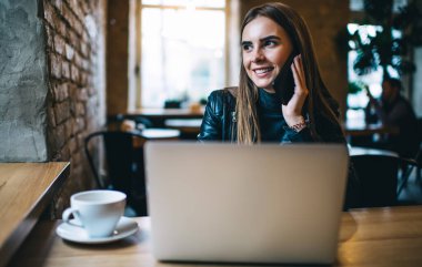 Neşeli kadın metin yazarı gülümserken iş arkadaşına web günlüğünde yayınlanan içeriği tartışması için sesleniyor. Laptop bilgisayarı olan mutlu, mobil sohbetin keyfini çıkaran Kafkasyalı serbest yazar.