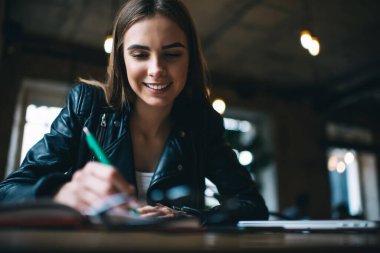 Ders kitabında eğitim bilgisi yazan neşeli bayan öğrenci, sınavlara hazırlanırken mutlu Kafkasyalı blogcu evde çalışırken ve üniversite ödevlerini yaparken gülümsüyor.